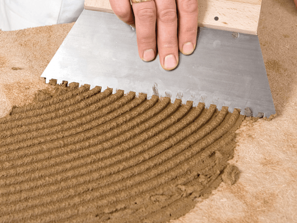 Mortier de collage et d’adhérence sous forme de mélange sec et prêt à l’emploi à grain fin pour le collage de panneaux légers de construction et d’isolation intérieure sur divers supports, comme mortier d’armature sur les panneaux de construction en argile, les panneaux d’argile et de chanvre, les panneaux isolants en fibres de bois et les panneaux de construction en fibres de bois ainsi que les panneaux en mousse minérale.