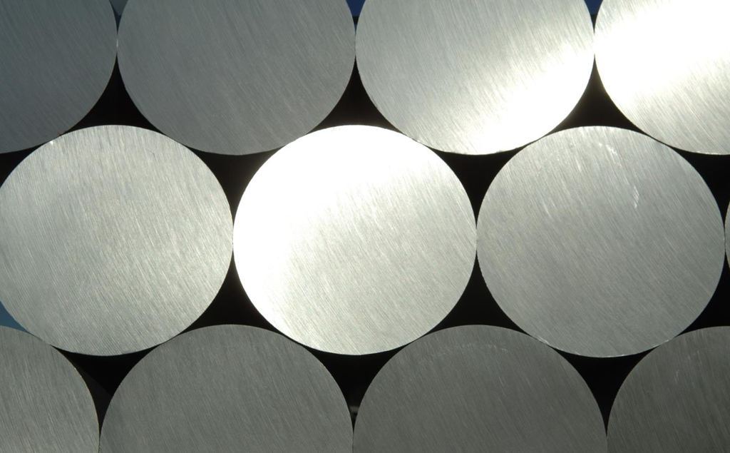 Hydro CIRCAL 100R est une gamme de lingots d'extrusion spécialement conçue pour l'économie circulaire, avec une teneur en déchets post-consommation (également appelés « déchets en fin de vie ») d'au moins 99,5 %. La plupart des déchets post-consommation utilisés sont broyés et triés afin d'éliminer tous les corps étrangers et d'assurer une teneur en aluminium proche de 100 %. Les déchets broyés sont ensuite traités dans la fonderie selon un procédé innovant et économe en énergie, au cours duquel ils subissent un processus de décapage. À ce stade, la matière organique est éliminée par pyrolyse : un gaz chaud à 500 °C brûle la peinture.
Le recyclage ne nécessite que 5 % de l'énergie requise pour la production de métal primaire (Hydro, 2023). Par conséquent, les émissions directes et indirectes des usines de recyclage de l'aluminium sont faibles par rapport aux émissions liées à la production d'aluminium primaire. De plus, les émissions indirectes liées aux matières premières sont minimes lors du recyclage de déchets sous forme de ferraille post-consommation, qui n'ont plus d'impact environnemental puisqu'ils ont atteint la fin de leur durée de vie utile et sont recyclés en nouveaux produits. En conséquence, l'impact du CIRCAL 100R sur le changement climatique (PRG total en kg CO2/kg Al) est minime par rapport aux autres filières de production d'aluminium (fig. 3), étant 32 fois inférieur à la moyenne mondiale pour l'aluminium primaire et 12 fois inférieur à la moyenne européenne.